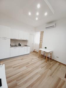 uma cozinha com armários brancos e piso em madeira em Vicolo 107 em Sannicandro di Bari
