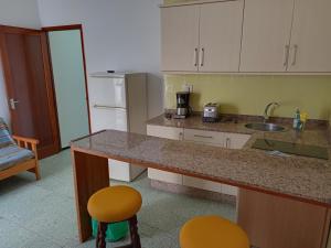 a kitchen with a counter and a sink and two stools at Pension Alvarez in El Tablero