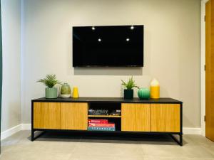 a black and wooden entertainment center with a television on a wall at LUCKY13@ The Tofts in South Cave