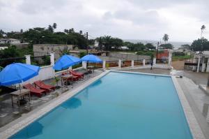 a large swimming pool with blue umbrellas and chairs at SEGMAD HOTEL in Kribi