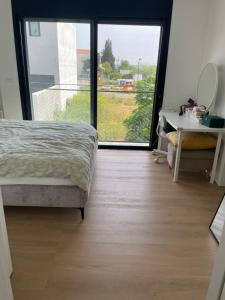 a bedroom with a bed and a desk and a window at Aloni House In Dagan in Even Yehuda