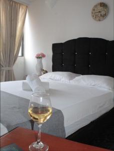 ネイバにあるHOTEL DINASTIA REAL NEIVAのベッドサイドのテーブルに座るワイン