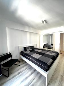 een slaapkamer met een zwart-wit bed en een stoel bij Spacious & Cozy Apartment in Pipera with Underground Parking & Self Check in-close to Baneasa Forest & Mall, and the airports in Voluntari