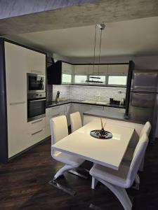 a kitchen and dining room with a white table and chairs at Apartman Daniela in Sarajevo