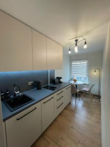 cocina con armarios blancos, fregadero y mesa en apartment SPRING, en Cēsis