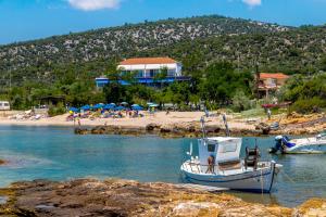 una barca in acqua vicino a una spiaggia con ombrelloni di Astris Beach ad Astrís