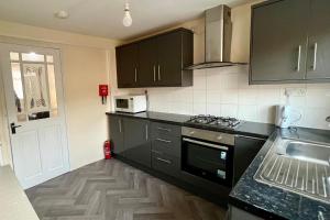 a kitchen with black cabinets and a sink at 3 Bedroom Holiday Home in Hackbridge