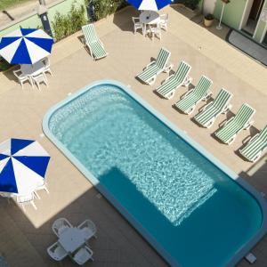 an overhead view of a swimming pool with chairs and umbrellas at Hotel Cores do Mar in Bombinhas