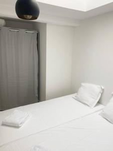 ein weißes Bett mit zwei Kissen und einem Spiegel in der Unterkunft NOUVEAU Maison Bourg Cournon 5 pers 2 chambres in Le Cendre