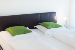 Una cama blanca con dos almohadas verdes. en Residence Ferienwohnungen Santner - Moderne zentrale Ferienwohnungen in Naturns Südtirol - mit Parkplatz, en Naturno