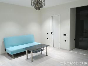 Comfortable Apartment في طشقند: أريكة زرقاء في غرفة بيضاء مع طاولة