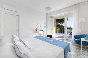 - une chambre blanche avec un grand lit et un balcon dans l'établissement Villa Kalu' with pool for up to 16 People, à Nerano