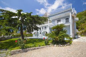 une maison blanche avec un palmier en face dans l'établissement Villa Kalu' with pool for up to 16 People, à Nerano