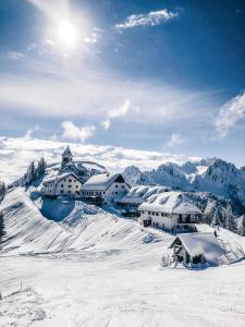 un pueblo cubierto de nieve en la cima de una montaña cubierta de nieve en Maggioni Silvia, en Tarvisio