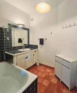 bagno con vasca, lavandino e specchio di TRES BEL APPARTEMENT VUE MER - Piscine - Tennis et Golf a Saint-Cyr-sur-Mer