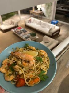 a blue bowl of shrimp spaghetti with a lemon wedge at Guest House Guarujá Hotel Boutique in Guarujá