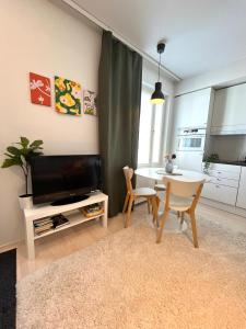 Una sala de estar con un televisor y una mesa con sillas. en Airport brand new 1BR apartment fully equipped, en Vantaa 7 fotos más