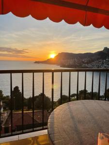 uma vista para o pôr-do-sol a partir de uma varanda em Aux portes de Monaco superbe T3 vue mer em Roquebrune-Cap-Martin