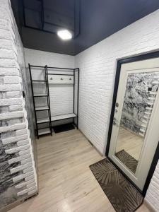 Cette chambre est dotée d'un mur en briques blanches et d'un miroir. dans l'établissement 1-комнатная квартира Виноградова 12, à Öskemen