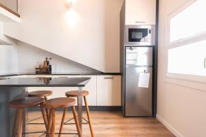 uma cozinha com um balcão, um frigorífico e bancos em Alojamento Porta14.4 em Chaves