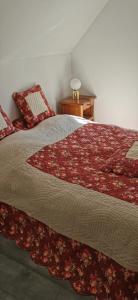 um quarto com uma cama com um edredão vermelho em Cottage LE NID em Perriers-en-Beauficel