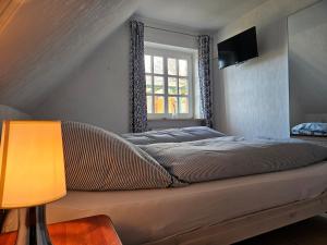1 cama en un dormitorio con ventana y lámpara en Ferienwohnung Leuchtturmblick en Pellworm