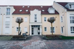 un bâtiment avec deux arbres devant lui dans l'établissement Design Apartment in Hallbergmoos, à Hallbergmoos