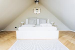 a white bed in a attic with a clock on the wall at Design Apartment in Hallbergmoos in Hallbergmoos