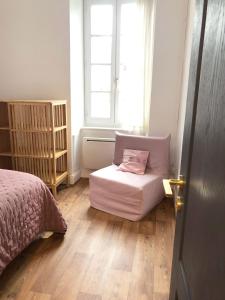 ein Schlafzimmer mit einem Bett und einem Stuhl mit einem Kissen in der Unterkunft Le songe d'Etigny in Luchon