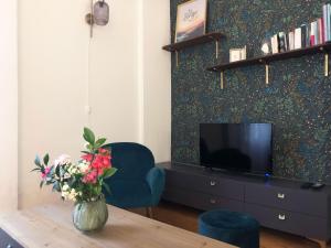 - un salon avec une télévision et une table fleurie dans l'établissement Le songe d'Etigny, à Luchon