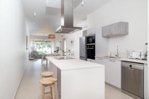a white kitchen with a white counter and stools at Ocean Point Beachfront Residences - Apartment A1 in Pointe aux Piments
