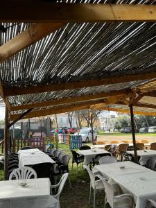 a group of tables and chairs under a wooden roof at Camping Erika in Paestum