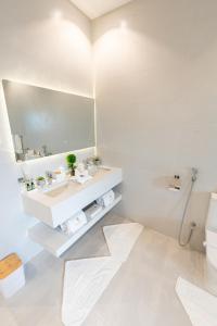 a white bathroom with a sink and a mirror at Tiffany Beach in Durat Alarous