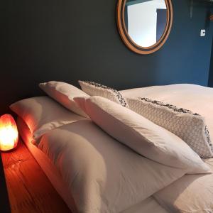 un letto con cuscini bianchi, posto accanto a uno specchio. di Recently extended garden apartment near JR and Oxford a Oxford