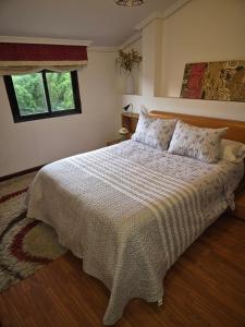 1 dormitorio con 1 cama con edredón blanco y ventana en Adosado playa Rodeira, en Cangas de Morrazo