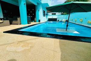 a swimming pool with an umbrella in the middle at Villa turquoise Exotique in Flic-en-Flac