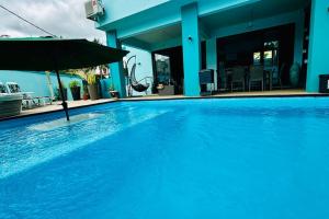 a large blue swimming pool with an umbrella at Villa turquoise Exotique in Flic-en-Flac