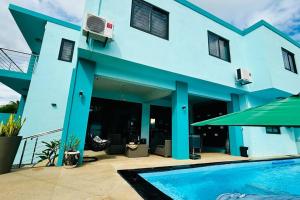 a blue house with a swimming pool in front of it at Villa turquoise Exotique in Flic-en-Flac
