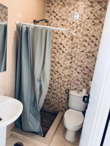 y baño con aseo y cortina de ducha. en Apartamentos Murallas Merinies, en Ceuta