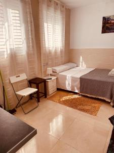 1 dormitorio con 2 camas, mesa y silla en Apartamentos Murallas Merinies, en Ceuta