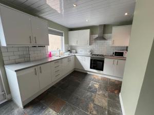 een keuken met witte kasten en een tegelvloer bij 3 bedroom sleeps 4 in Glenrothes in Fife