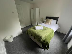 a bedroom with a bed with a green blanket at 3 bedroom sleeps 4 in Glenrothes in Fife
