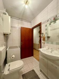een badkamer met een toilet, een wastafel en een rode deur bij Alessandra in Fusine in Valromana