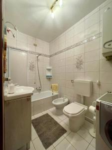 a bathroom with a toilet and a sink and a tub at Alessandra in Fusine in Valromana