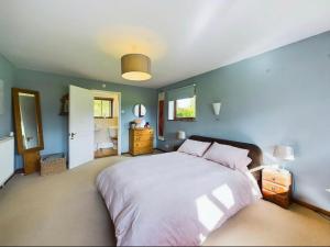 a bedroom with a large bed and a blue wall at Idyllic Devon Haven: 3BR Bungalow by Moors/Beaches in Cullompton