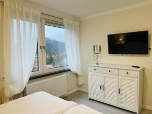 a bedroom with a large window and a tv on the wall at Maison Lily Apartment 4 in Bad Lauterberg