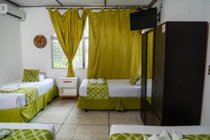two beds in a room with yellow curtains at Suites & Apartments San Benito - Zona Rosa in San Salvador +157 photos