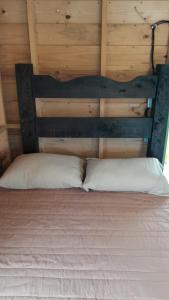 1 cama con cabecero de madera y 2 almohadas blancas en CABAÑA RURAL DURANGO, en Salento