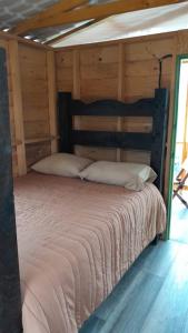 Cama grande en habitación con paredes de madera en CABAÑA RURAL DURANGO, en Salento