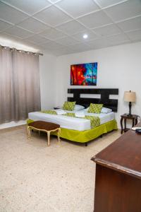 a bedroom with two beds and a table and a desk at Suites & Apartments San Benito - Zona Rosa in San Salvador
